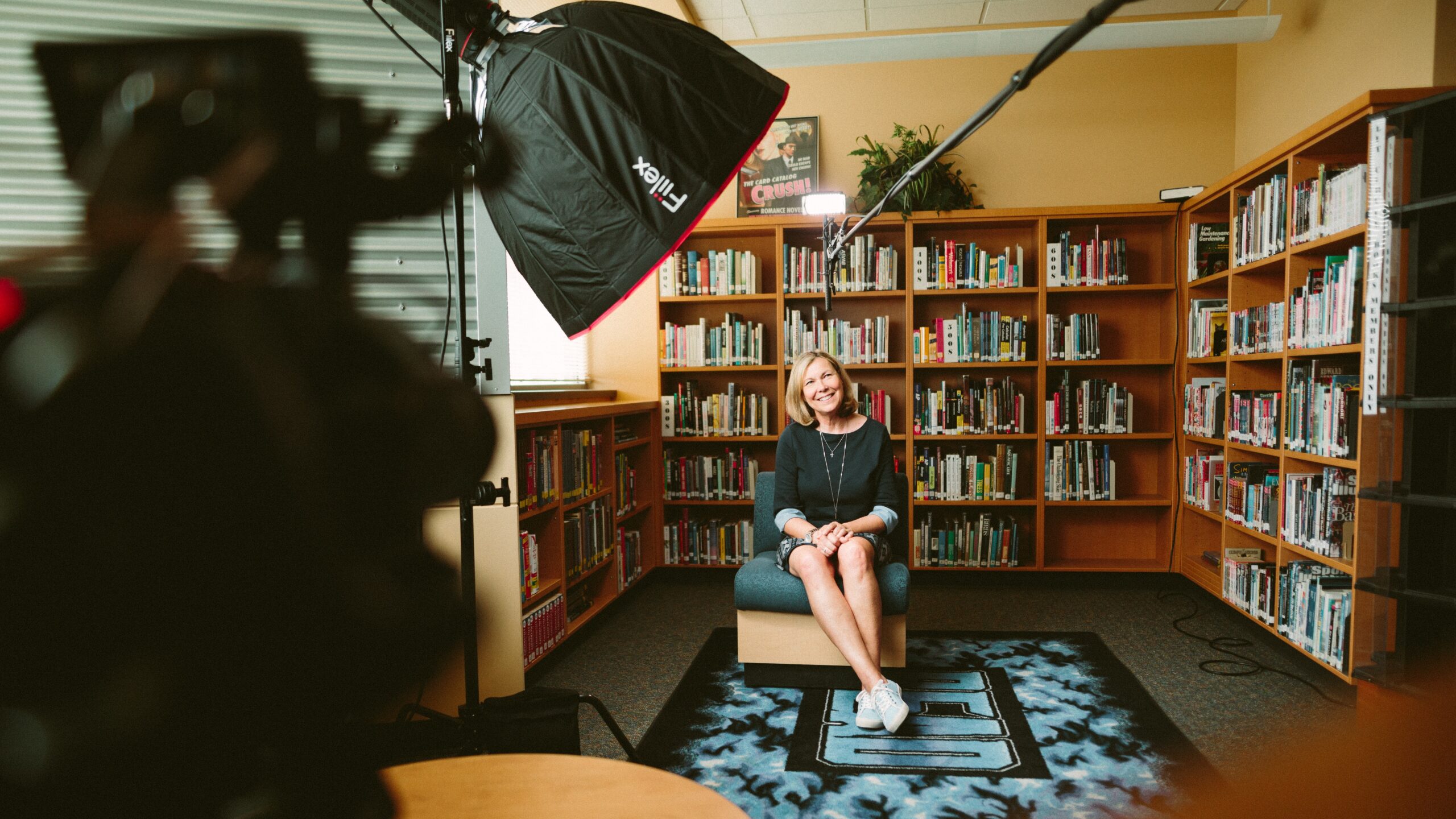 A lady is happily sitting in a library being interviewed during a half-day shoot by Concept Films.
